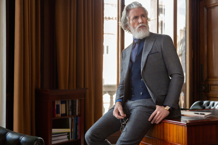 A man with a white beard sits in a chair, exuding a calm and thoughtful demeanor